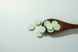 Group of medicine pills and antibiotics, White medical tablets, light green, with wooden spoon, with copy space. photo