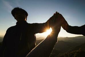 silhouette of Teamwork of three  hiker helping each other on top of mountain climbing team. Teamwork friendship hiking help each other trust assistance silhouette in mountains, sunrise. photo