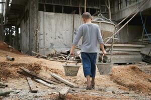 Poor little boy working at construction site, human trafficking, poor child labor. World day against child labour concept. photo