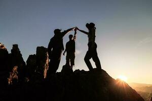 Silhouette of  happy teamwork hold hands up as a business successful, business victory, achieve business goal, Teamwork helping hand trust assistance. photo