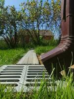 drainage systems. metal structure from the roof. sewer and grate on the ground to drain water. photo