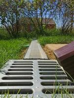 drainage systems. metal structure from the roof. sewer and grate on the ground to drain water. photo