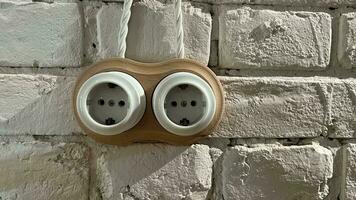 White socket on the background of a white brick wall. Retro socket vintage style. Electricity in the interior. photo