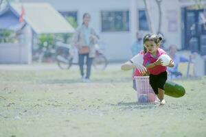 niña participación un blanco pelota en su manos, corriendo en el parque, jugando con su para niños amigos. foto