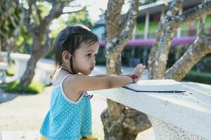 Side view of asian girl sitting on a bench and reading a book in the park. photo