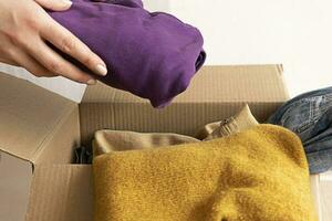 Woman packs clothes in boxes for donating. photo