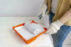 Womens hands using paint roller while working indoors photo