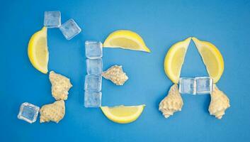 Sea, summer word with ice cube, lemon and shells. Flat lay on blue background photo