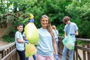 Group of volunteers cleaning up forest from waste, community service concept photo