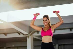 Strong fit woman working out with dumbbells. Attractive fit woman works out with dumbbells as a fitness conceptual. Active woman in sportswear working out. photo