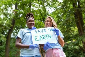 Two volunteers of different races hold a paper and show how important it is to take care of the environment. Volunteering concept. photo