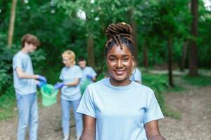 A multiethnic group of people, cleaning together in a public park, are protecting the environment. The concept of recycling and cleaning photo