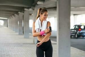 Portrait of adorable charming smiling young shape fitness girl with earphones holding a towel and posing. Fitness woman taking a break after running workout. photo