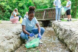 Woman handpicking gathering up garbage plastic straws garbage from the river at the park. World environment day.Environment concept. photo