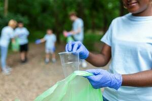 A multiethnic group of people, cleaning together in a public park, are protecting the environment. The concept of recycling and cleaning photo