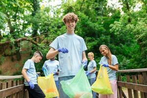 Multiracial group of volunteers taking care of nature ecology and picking garbage in plastic bags cleaning ground. photo