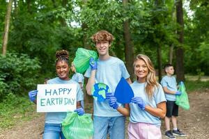 Diverse Group of People Picking Up Trash in The Park Volunteer Community Service. Happy international volunteers holding placard with 'happy Earth day' message. photo