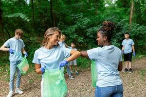 Young responsible people doing community charity work in the park. Group of people, cleaning together in public park, saving the environment. photo