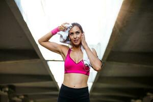 Young smiling female resting after an active fitness training while standing against gray wall with copy space area for your text message, satisfied fit woman resting after an active fitness training photo