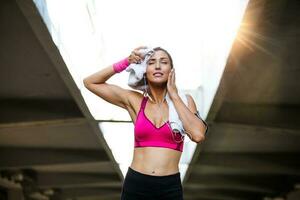 Young smiling female resting after an active fitness training while standing against gray wall with copy space area for your text message, satisfied fit woman resting after an active fitness training photo