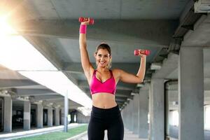 Athletic woman doing exercise for arms. Fitness model working out with dumbbells. Woman exercising with dumbbells. Fitness, workout, healthy living and diet concept. woman doing gymnastic exercises. photo