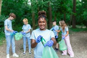Group of young people friends volunteers collecting plastic bottles to trash bags in forest. Ecology concept photo