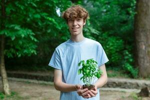 joven hombre participación un planta creciente fuera de suelo foto