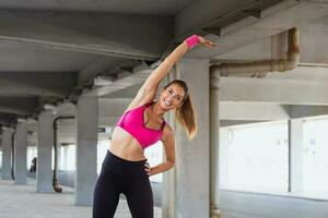 sano Deportes estilo de vida. atlético joven mujer en Deportes vestir haciendo aptitud ejercicio. aptitud mujer extensión brazos antes de correr foto