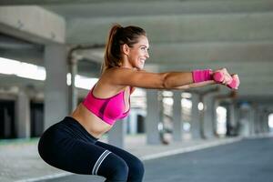 Sporty woman exercising with dumbbells. Photo of active woman in sportswear working out. Dynamic movement. Side view. Sport and healthy lifestyle