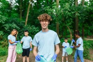 Young responsible people doing community charity work in the park. Group of people, cleaning together in public park, saving the environment. photo