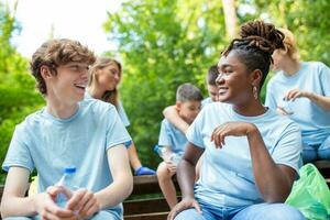 espontáneo imagen de un pequeño grupo de voluntarios con guantes y basura pantalones haciendo un detener mientras en el parque ellos han sólo limpiado todas vistiendo azul camisetas, siendo orgulloso y contento para qué ellos hizo foto