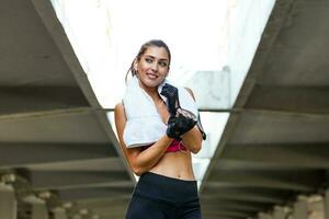 Young sporty woman putting on her training gloves. Woman Doing Workout Exercises On Street. Beautiful Athletic Fit Girl Stretching And Relaxing After Fitness Training photo