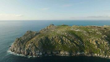 oceano onde spruzzi su il costa di sisargas isola con un vecchio faro a il superiore, collocato nel galizia, Spagna. aereo, ingrandire video