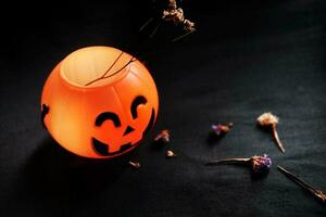 Halloween pumpkin head with dry flowers on black clothes in natural shadow and light. Halloween holiday concept. photo