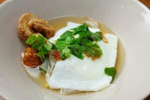 Delicious Fried noodle Thai style with Fried pork crackling, lemon sliced with Bean sprouts and fried egg, coriander topping in white bowl. Traditional local Thai sreet food photo