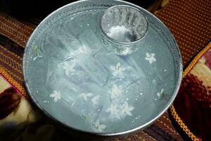 Fresh Cold water with ice and jasmine flowers in vintage silver bowl is traditional for drinking on summer season in countryside of Thailand photo