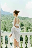 mujer en un blanco camisa admira el verde naturaleza en el balcón relajación concepto foto