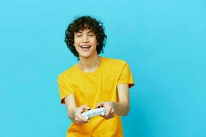 curly guy plays with joystick in yellow t-shirts Lifestyle entertainment photo