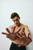 A man with a naked torso gestures with his hands in front of his face cropped view photo