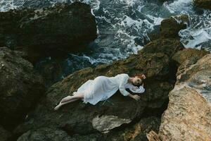 sensual woman lying on rocky coast with cracks on rocky surface landscape photo