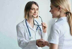 beautiful woman doctor with stethoscope shaking hands with female patient photo