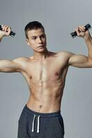 athletic guy with a pumped-up body in shorts with dumbbells in his hands photo