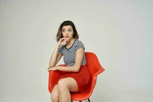 beautiful woman with glasses sitting on the red chair posing Studio photo