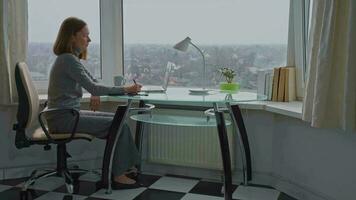 donna seduta a il scrivania nel camera con grande finestra video