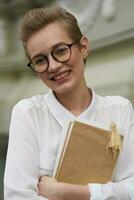 short haired woman with glasses walking around the city with a book communication photo