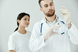 woman patient looking at syringe in doctor's hand vaccination coronavirus light background photo