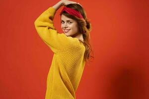 woman in yellow sweater with bandage on her head fashion red background studio photo