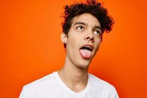 chico con Rizado pelo en un blanco camiseta emoción mueca foto