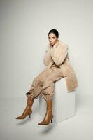 pretty woman in fashionable clothes brown boots light background photo