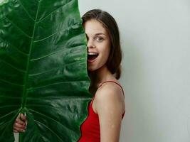 woman covers half of the leaf with green palm leaf close-up photo